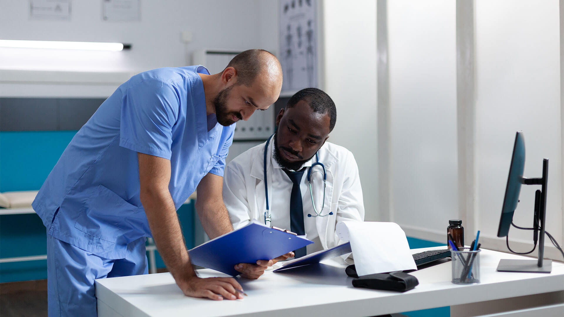 Médico e enfermeiro conversando e analisando laudo médico em um consultório